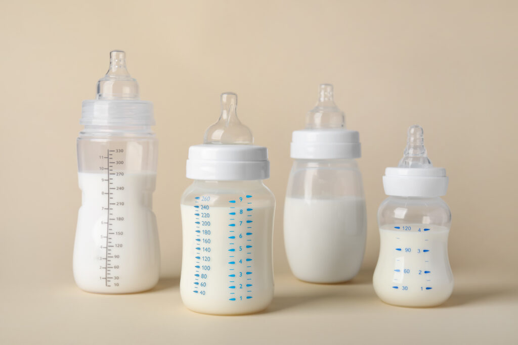 Feeding bottles with baby formula on beige background